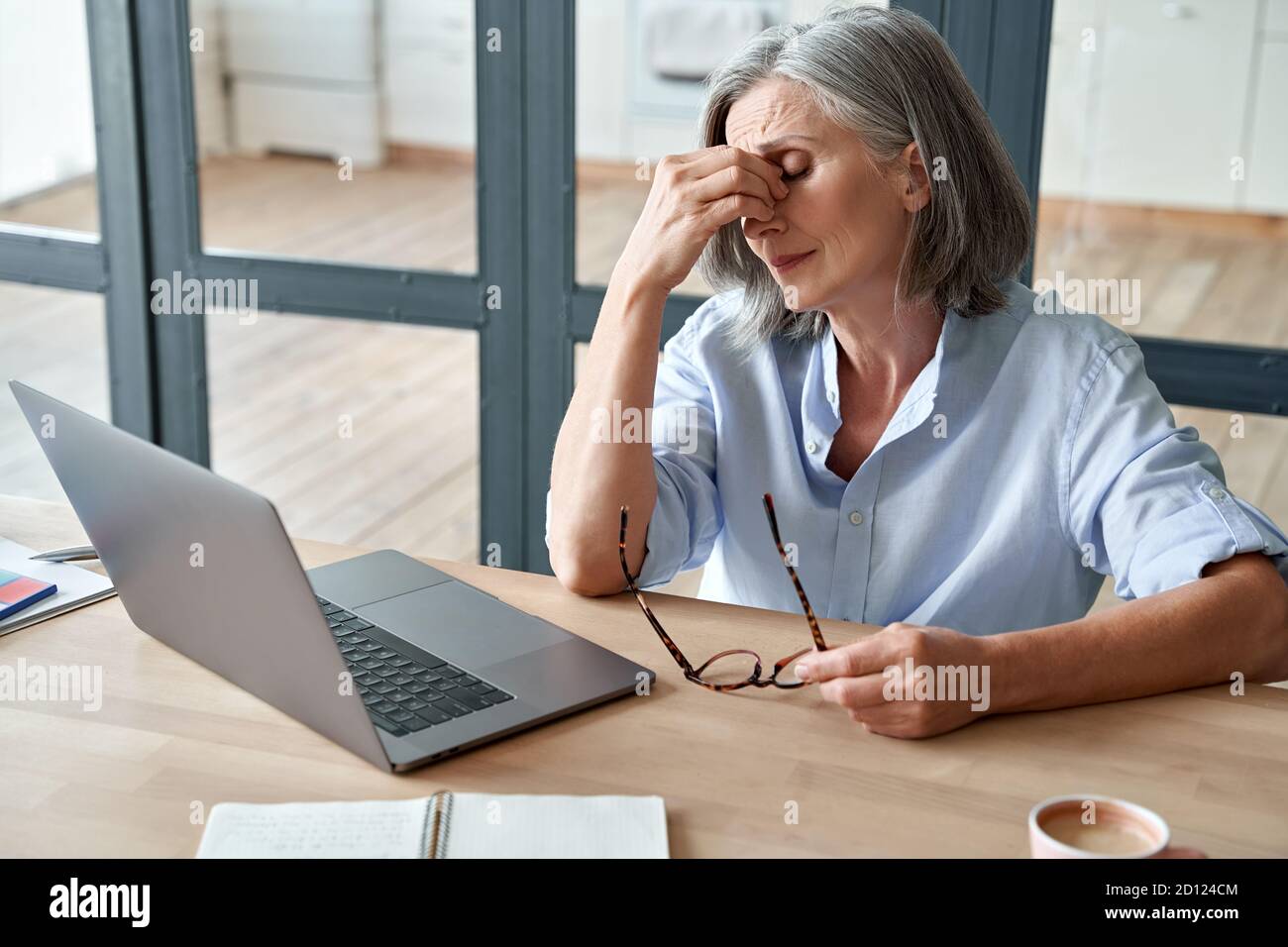Überarbeiteter müde alte Dame hält Brille Gefühl Kopfschmerzen nach Computer-Arbeit. Stockfoto