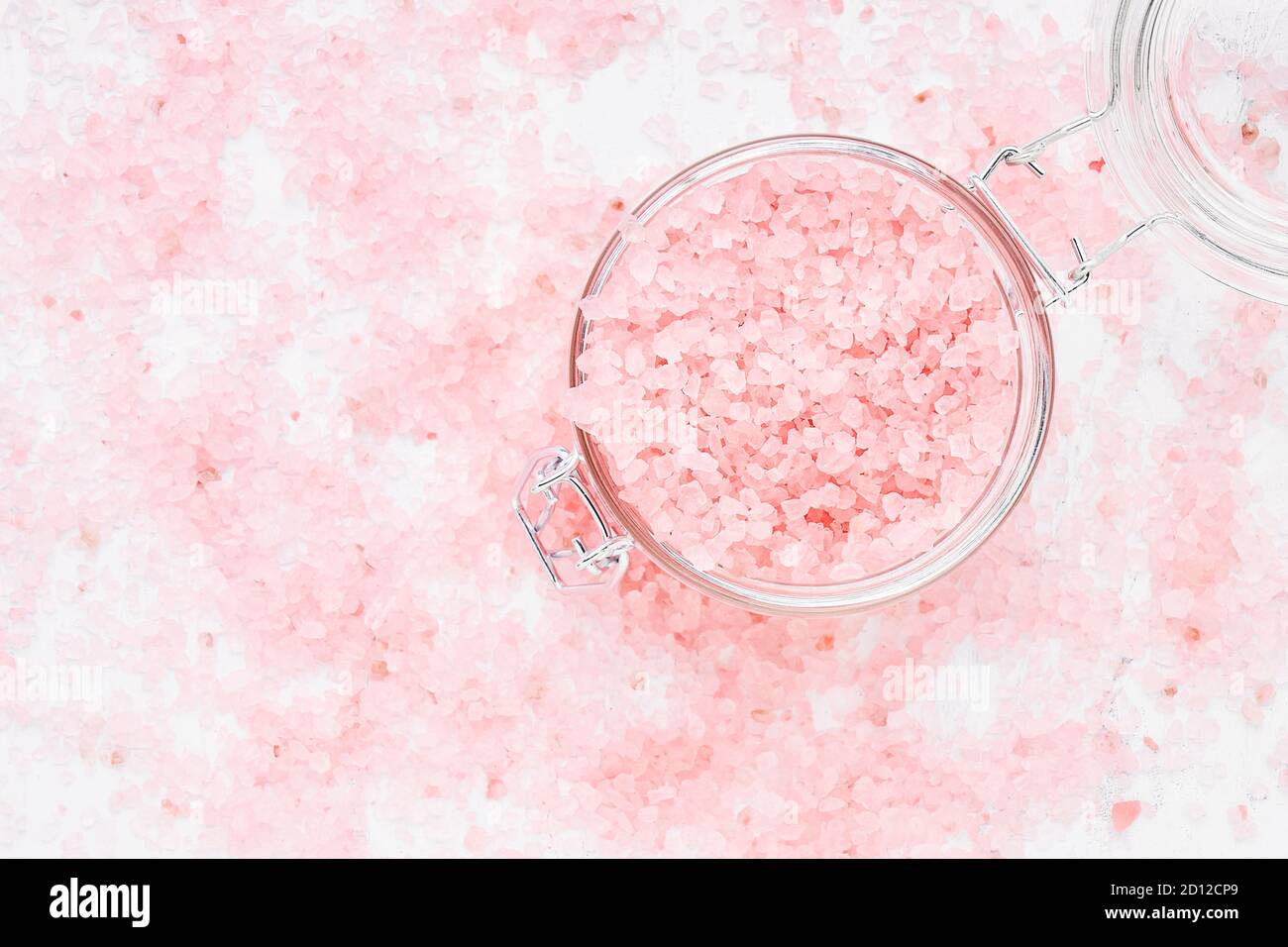Rosa Aroma Badesalz in einem Glas auf rosa Badesalz Hintergrund. Spa, Hautpflege-Konzept. Draufsicht, Kopierbereich für Text. Selektiver Fokus Stockfoto