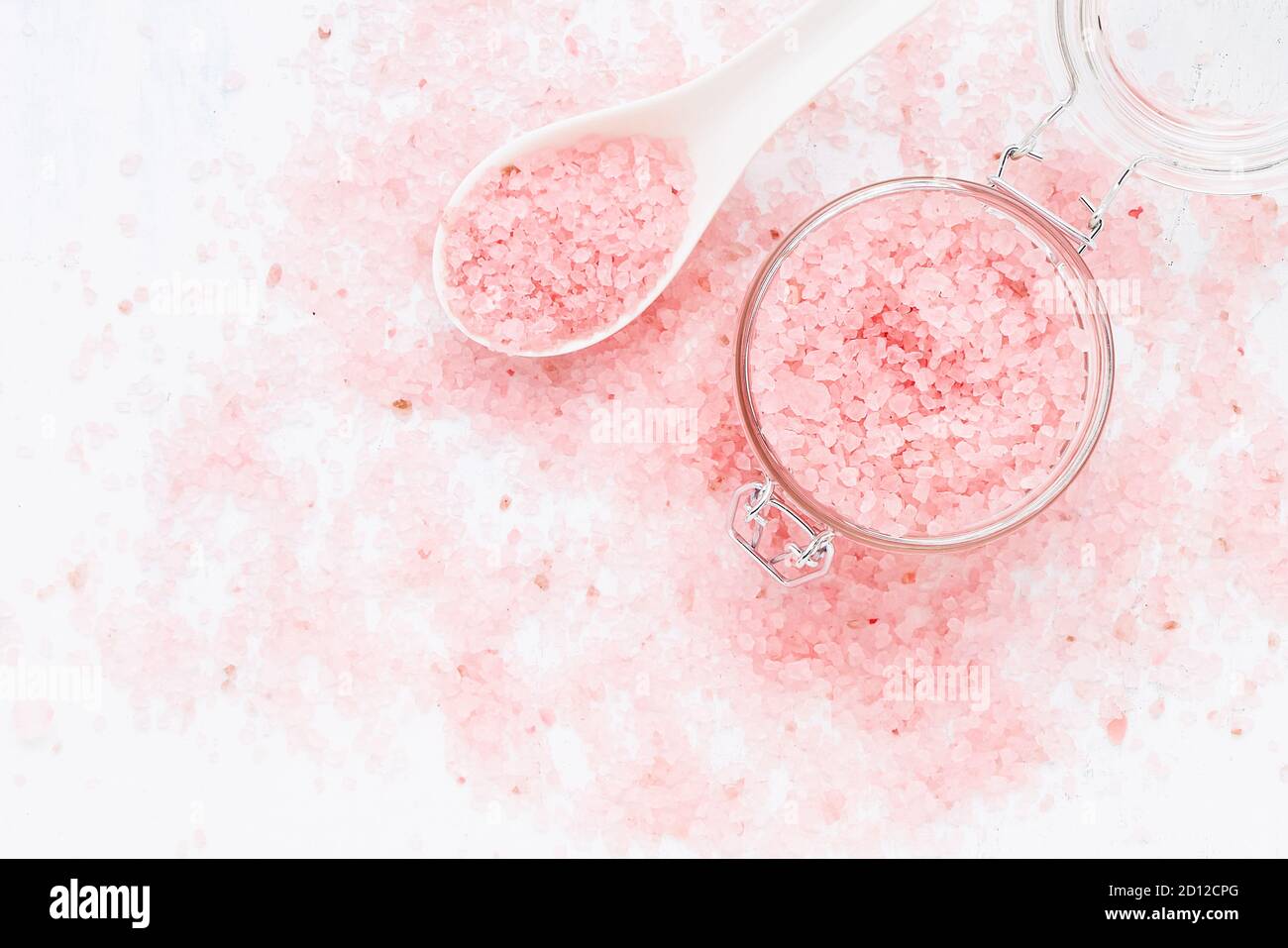 Rosa Aroma Badesalz in einem Glas auf rosa Badesalz Hintergrund. Spa, Hautpflege-Konzept. Draufsicht, Kopierbereich. Selektiver Fokus Stockfoto