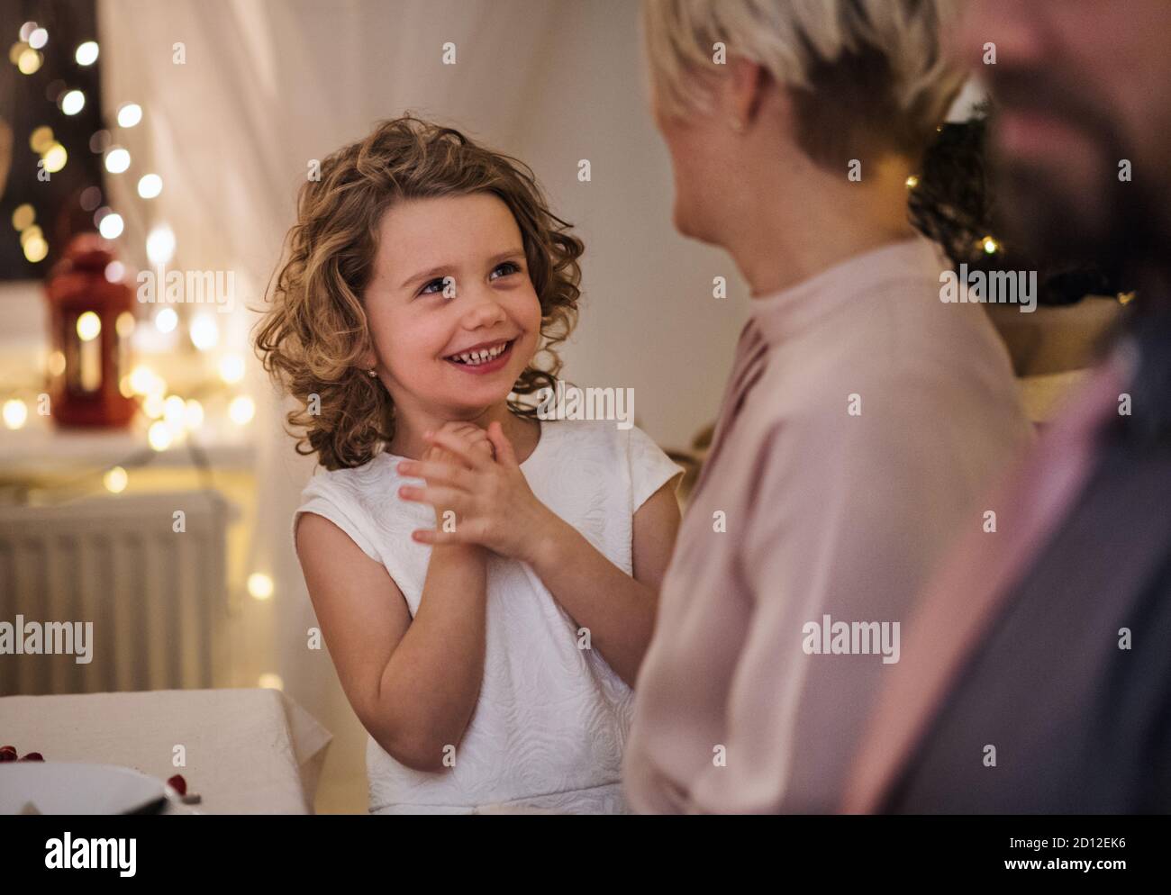 Kleines Mädchen mit Eltern am Tisch drinnen Weihnachten feiern zusammen. Stockfoto