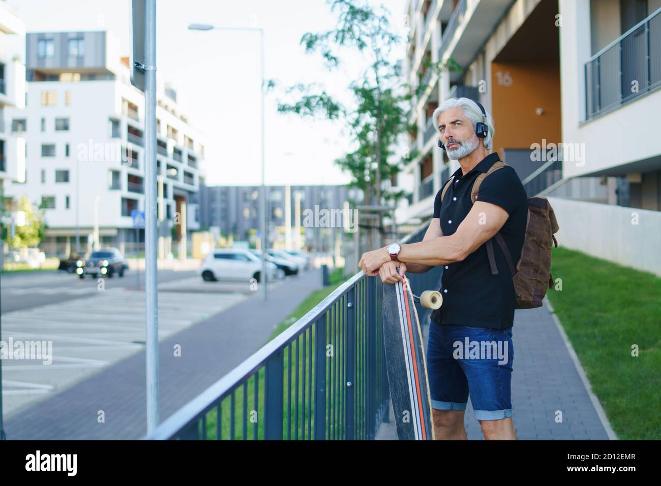 Portrait von reifen Mann mit Skateboard im Freien in der Stadt, gehen zurück zur Arbeit. Stockfoto