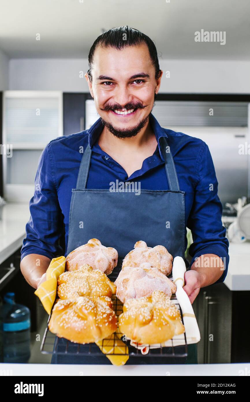 Mexikanischer Mann backen Brot genannt Pan de muerto traditionell aus Mexiko an Halloween Stockfoto