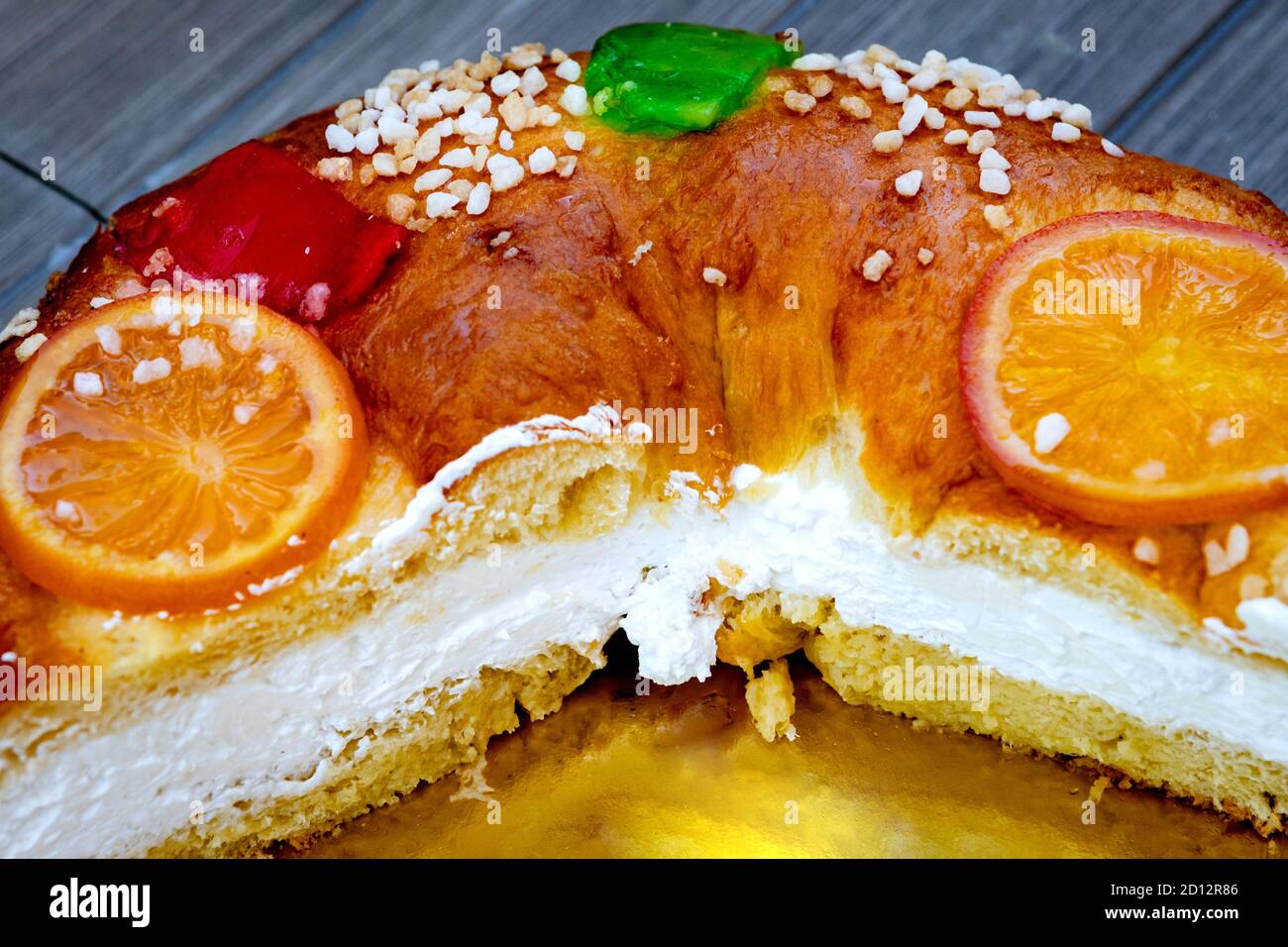 Weihnachtliche runde Obstkuchen mit Tannenzweigen, glasierten Früchten und Nüssen auf einem hölzernen Hintergrund. Stockfoto