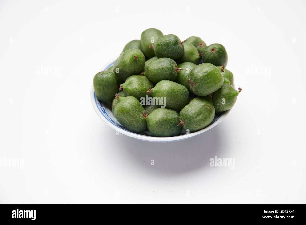 Kiwi-Beeren (Actinidia arguta) in einer kleinen weißen Schüssel auf einer weißen Arbeitsplatte. Stockfoto