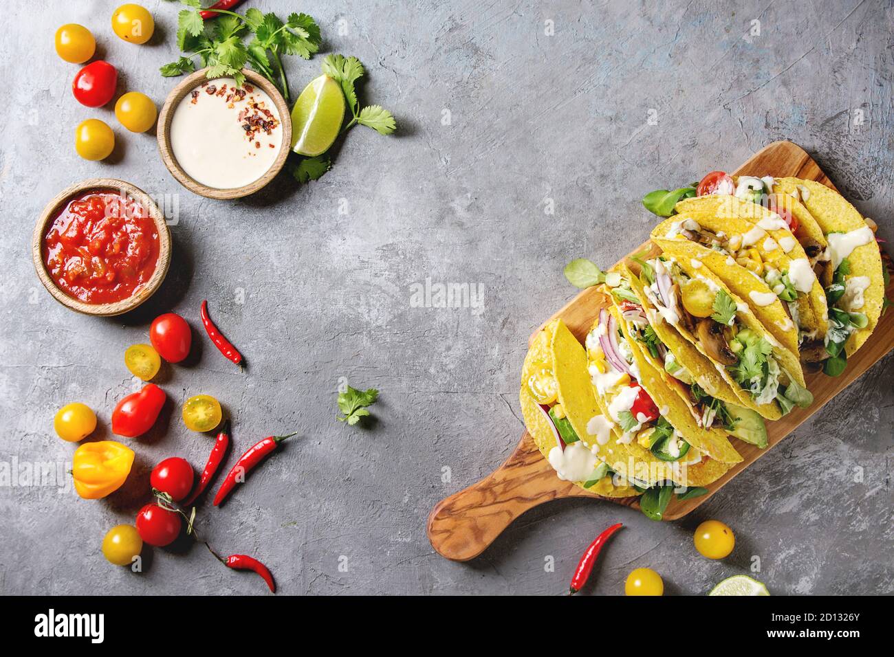 Auswahl an vegetarischen Mais Tacos mit Gemüse, Salat, Chili Pfeffer auf olivenholz Brett mit Tomaten serviert, Sahne Saucen mit Zutaten abov Stockfoto
