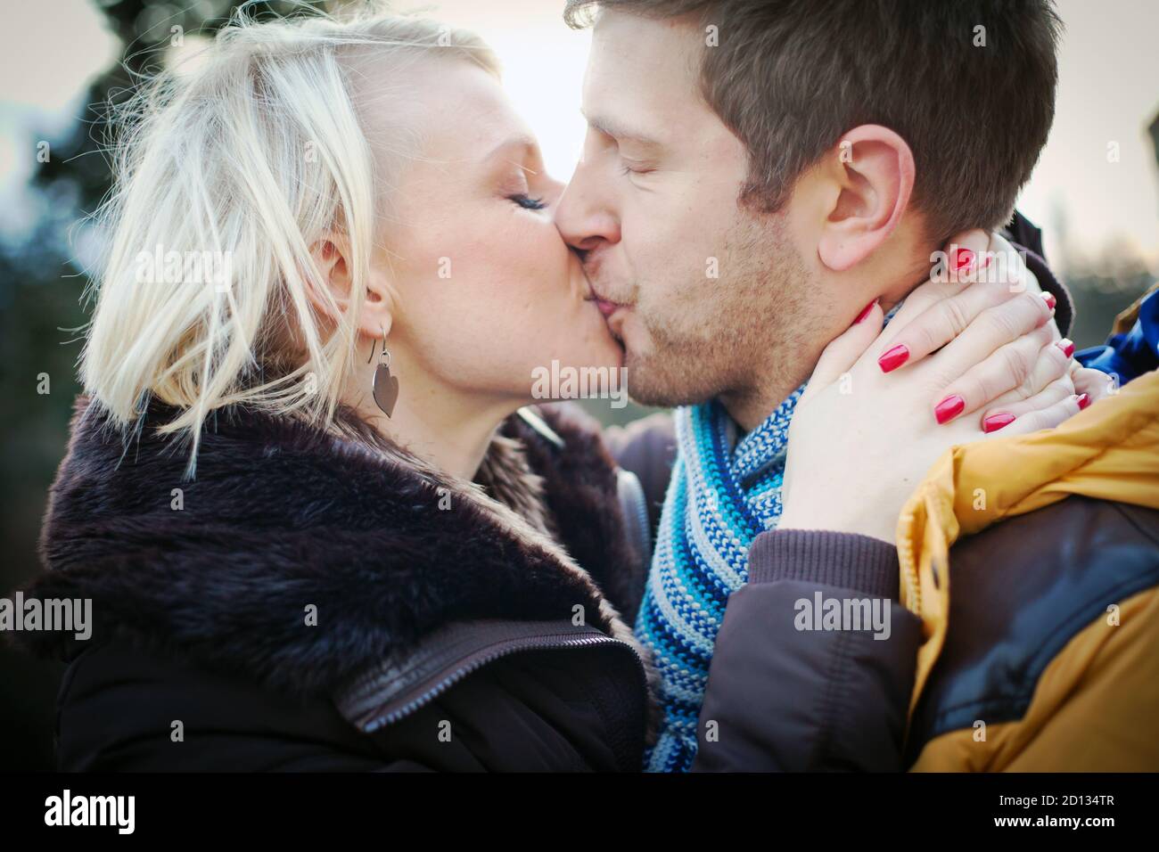 Junges Paar küsst draußen an einem kalten Wintertag. Stockfoto