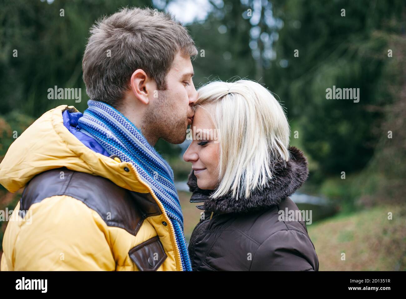 Junges Paar küsst draußen an einem kalten Wintertag. Stockfoto