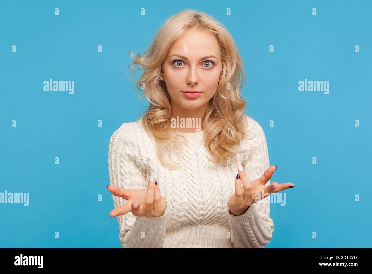 Nervös wütend Frau mit lockigen blonden Haaren spreizen Hände Blick auf die Kamera mit großen Augen, Missverständnis. Was wollen Sie? Innenaufnahmen im Studio Stockfoto
