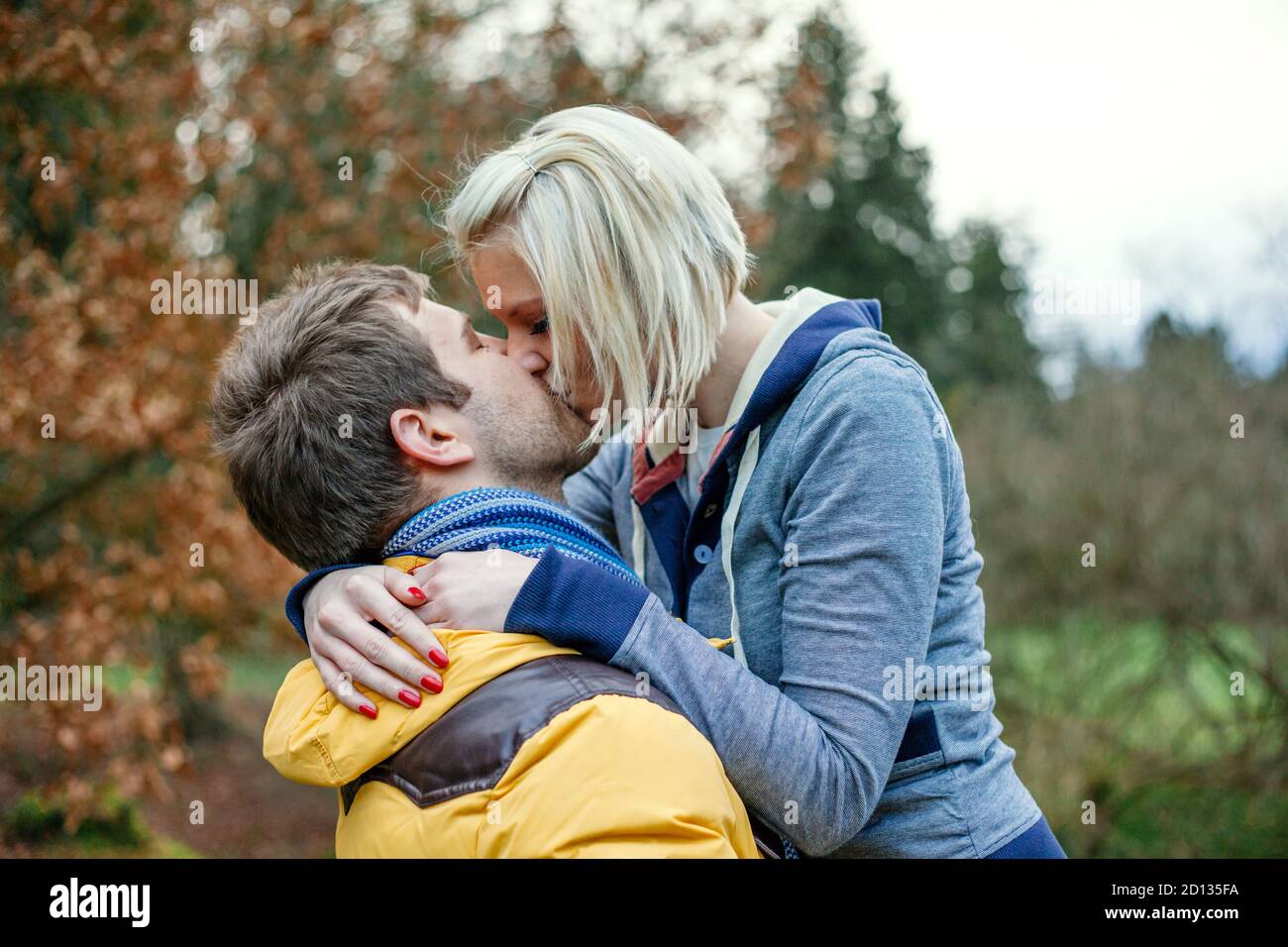 Junges Paar küsst draußen an einem kalten Wintertag. Stockfoto