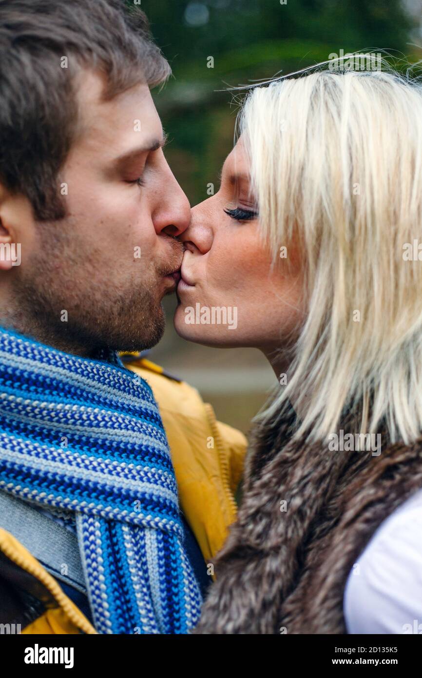 Junges Paar küsst draußen an einem kalten Wintertag. Stockfoto