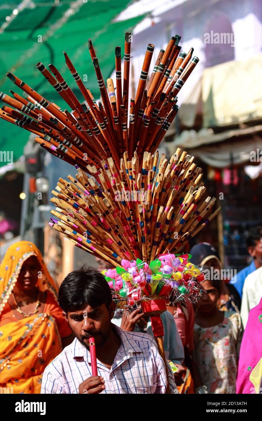 Ein Mann, der Flöten und Plastikspielzeug verkauft, das auf seiner Schulter auf den Straßen von Pushkar, Rajasthan, Indien, am 10. November 2018 angezeigt wird Stockfoto
