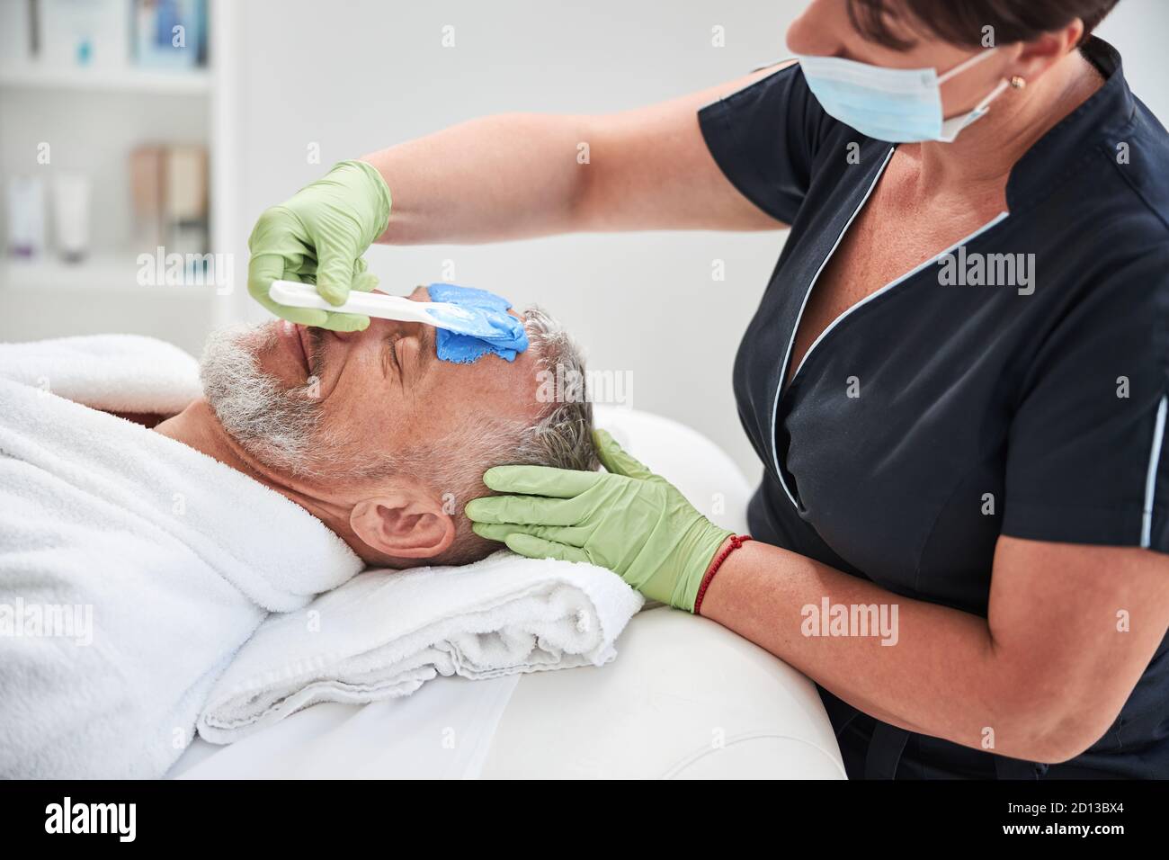 Professionelle Spa-Arbeiter tun Hautpflege Verfahren für einen alternden Mann Stockfoto