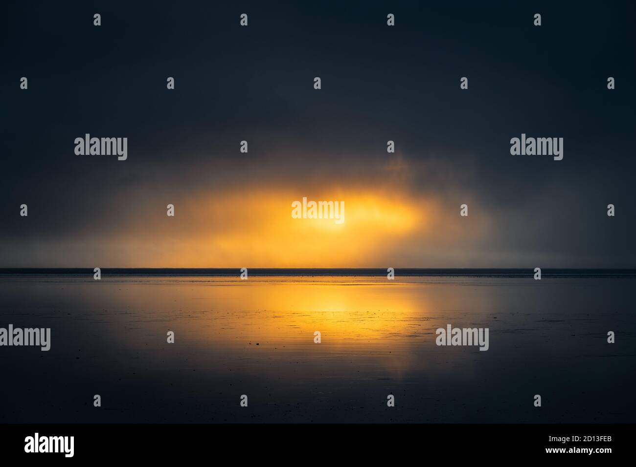 Dunkle Wolken und etwas Licht bei Sonnenaufgang in Lonsfjördur. Stockfoto
