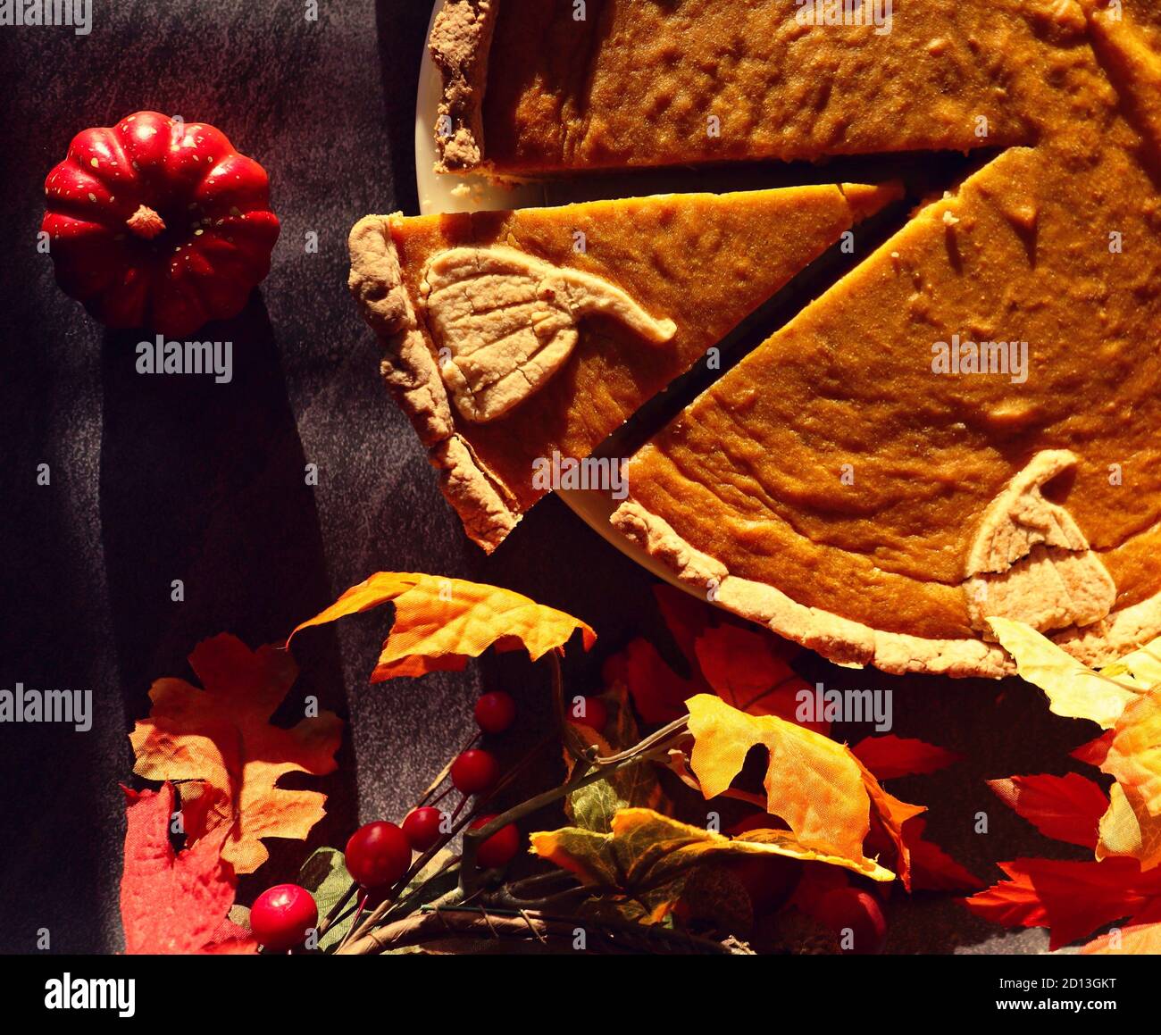 Nahaufnahme von Top-Down-Kürbiskuchen mit kleinen dekorativen Kürbis und künstlichen Herbstblättern. Food-Dekor mit Herbst und Oktober Vibes. Stockfoto