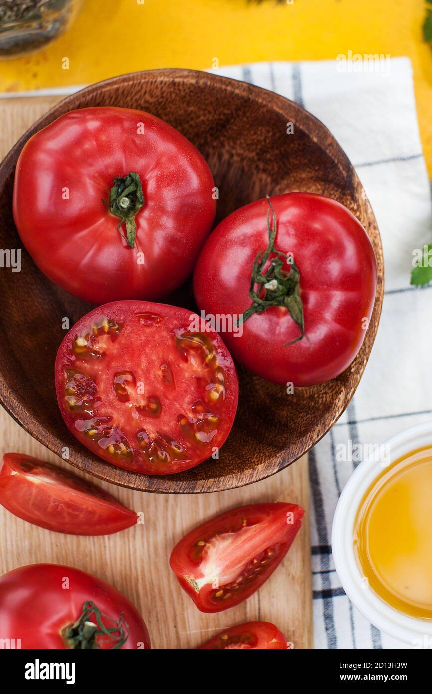 Reife rote und rosa Tomaten ganz und auf einem Holzbrett geschnitten. Food Foto für ecomarket. Stockfoto