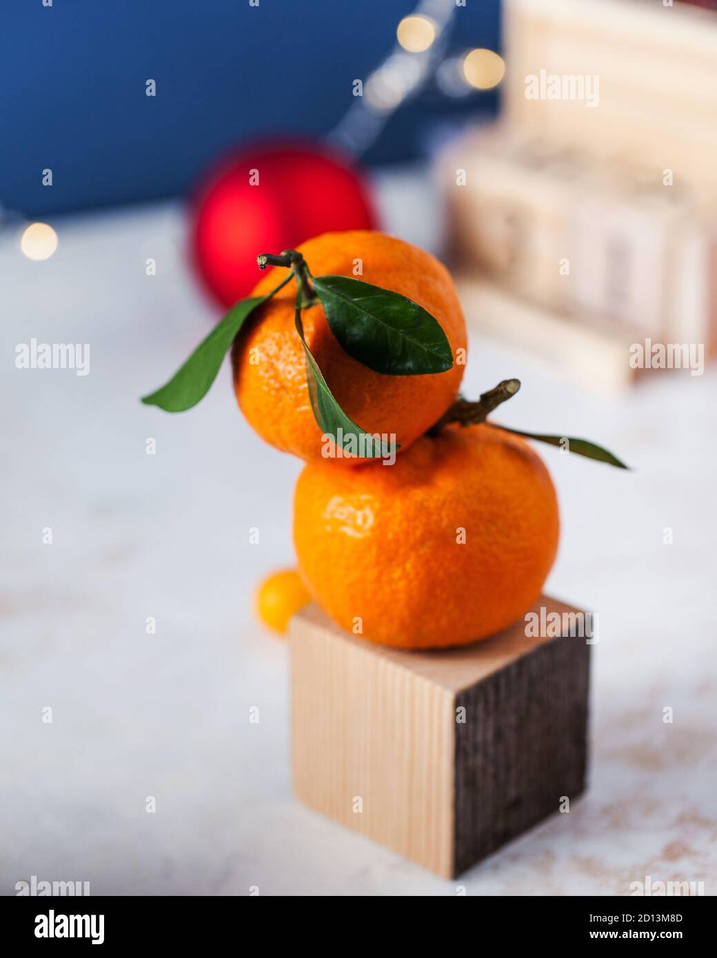 Mandarinen mit grünen Zweigen und Blättern mit Weihnachtsspielzeug. Der Hintergrund ist eine klassische blaue Farbe zum 2020 Trend. Stockfoto