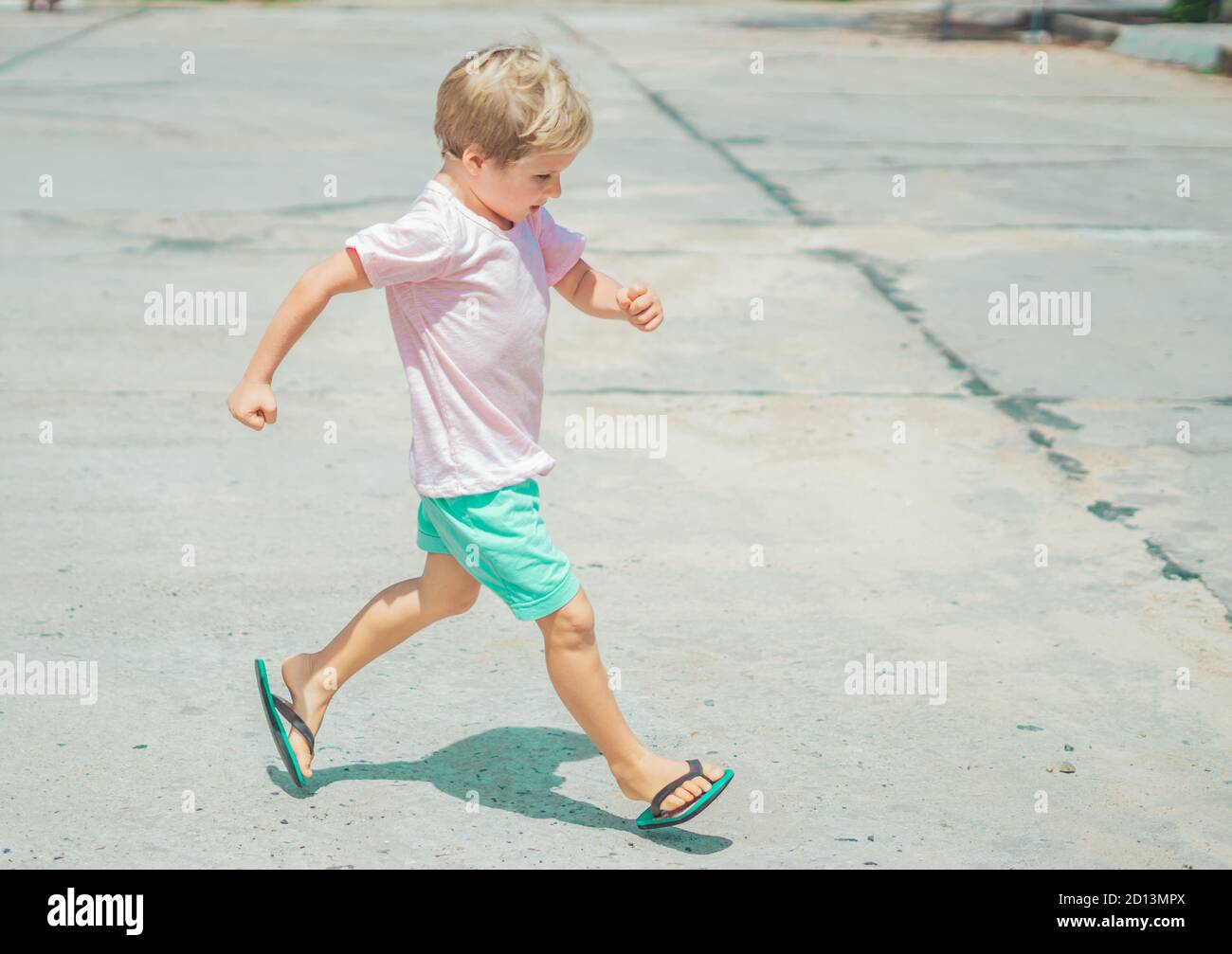 Lächelnd Sommersprossen blonde junge autistische Gesichtsausdrücke, laufen marschierenden Händen Gesten, schelmisch in guter Stimmung, Sommer Flip Flops Sandale. Lustiges Foto Stockfoto