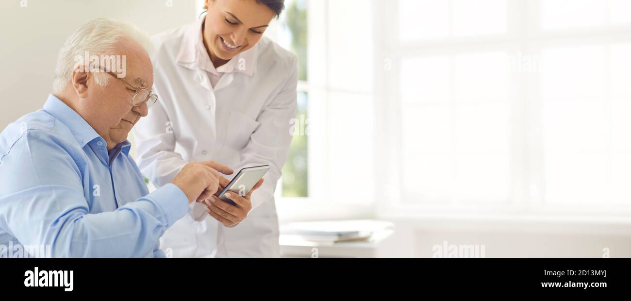 Freundlicher Arzt lehrt Senior man spezielle mobile App zu verwenden Zur Verfolgung verschiedener Integritätsindikatoren Stockfoto