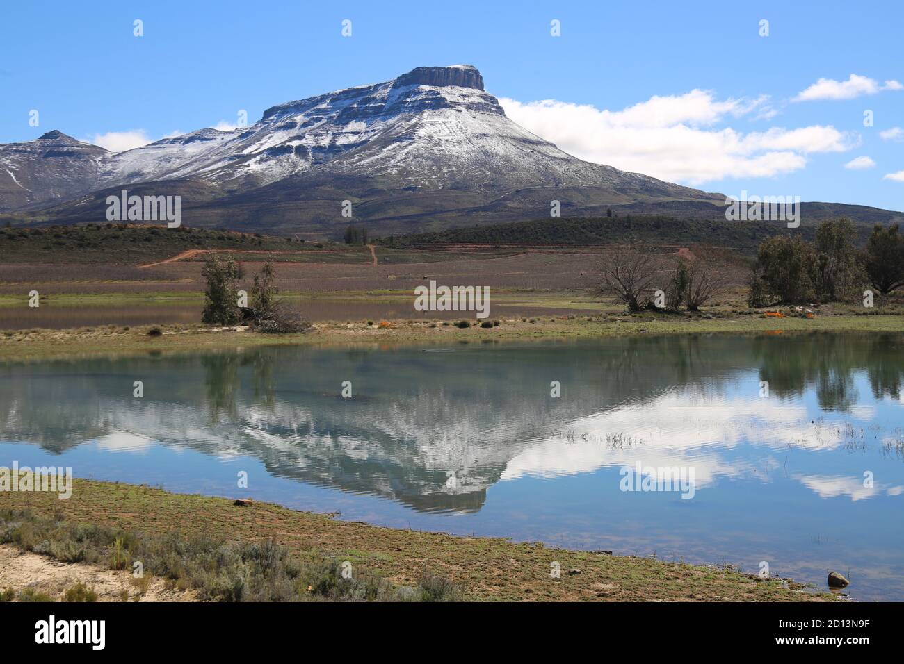 Die schneebedeckten Koue Bokkeveld Mountains in der Nähe von Op-die-Berg spiegeln sich in einem Damm An einem klaren Tag im Winter Stockfoto