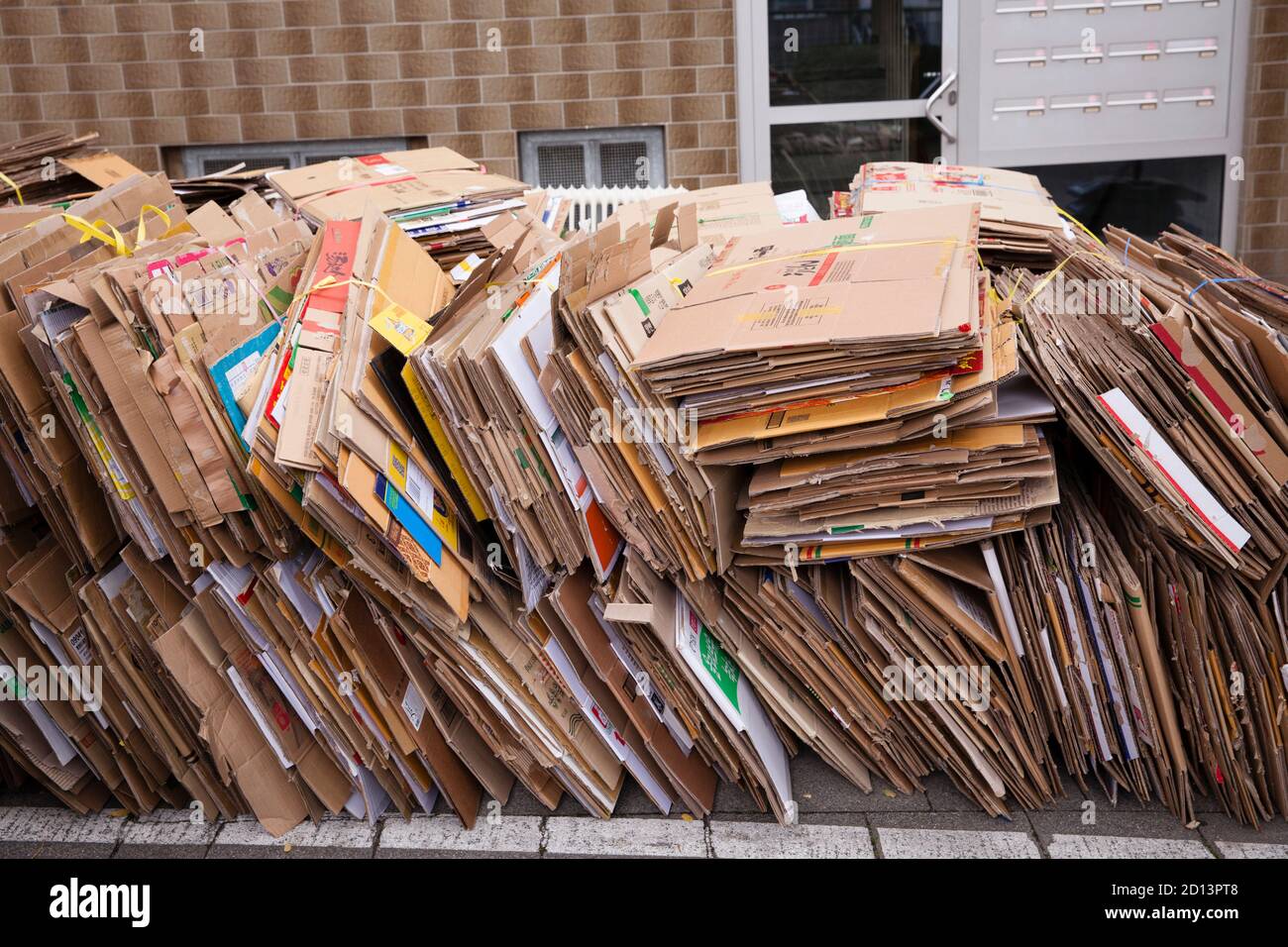 Zerlegte und gebündelte Kartons liegen auf dem Bürgersteig zur Entsorgung, Köln, Deutschland. Zerlegte und gebuendelte Pappkartons liegen zum Abtransport Stockfoto