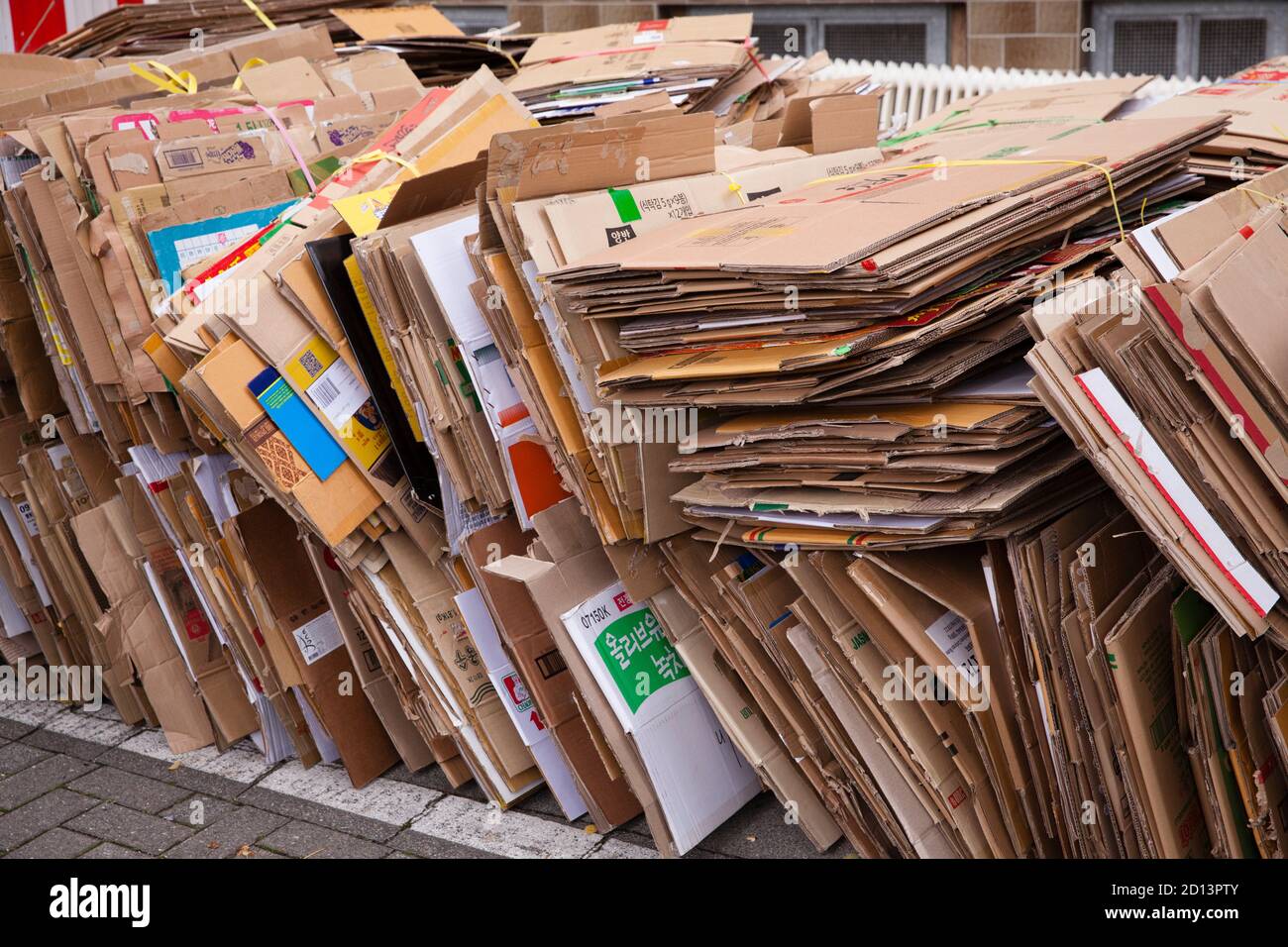Zerlegte und gebündelte Kartons liegen auf dem Bürgersteig zur Entsorgung, Köln, Deutschland. Zerlegte und gebuendelte Pappkartons liegen zum Abtransport Stockfoto