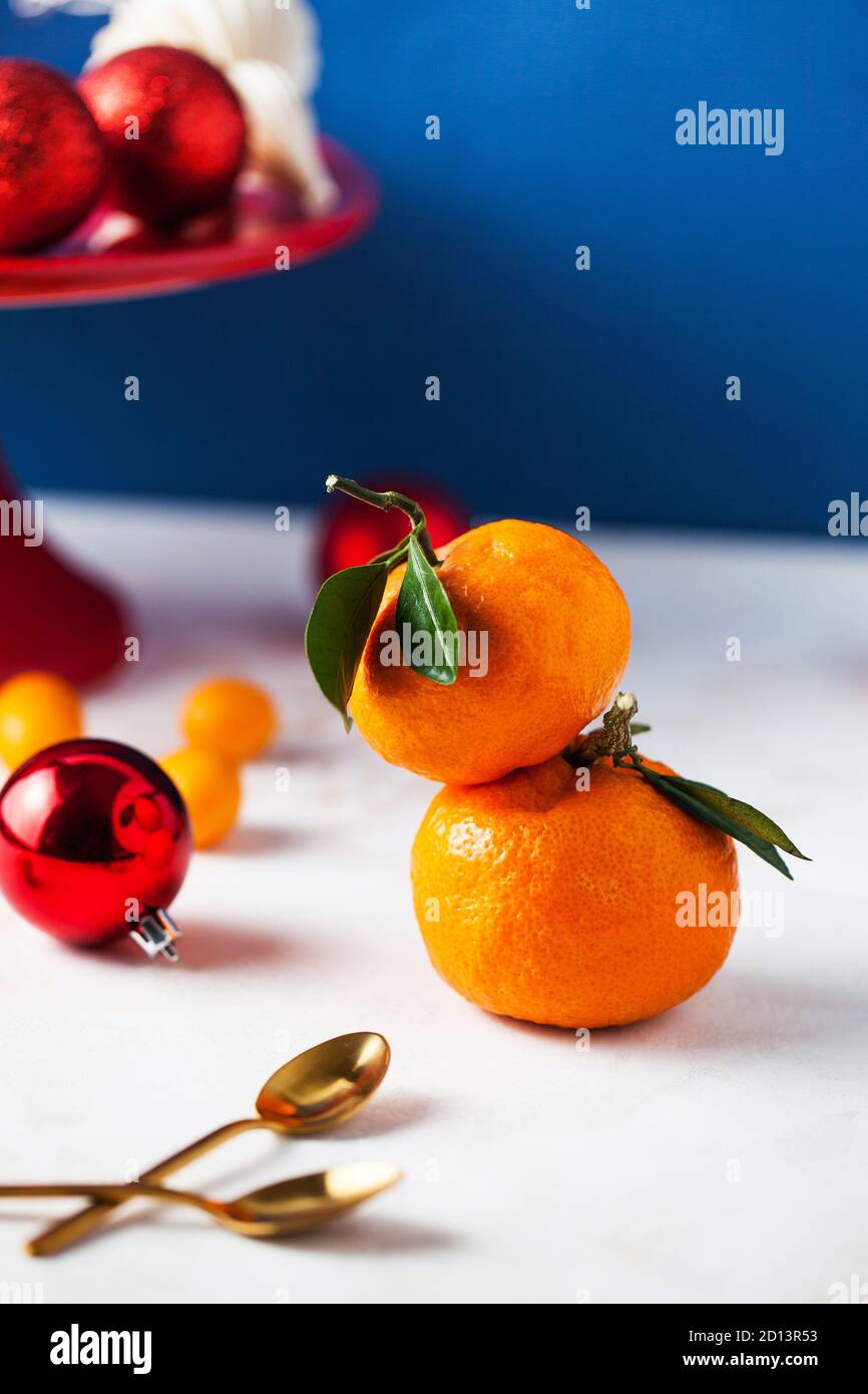 Mandarinen mit grünen Zweigen und Blättern mit Weihnachtsspielzeug. Es gibt Platz für Text. Stockfoto