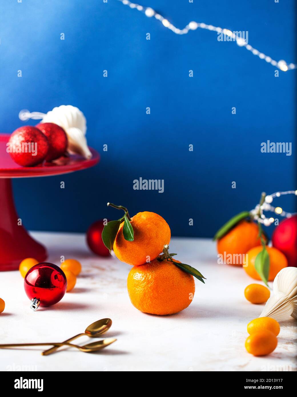 Mandarinen mit grünen Zweigen und Blättern mit Weihnachtsspielzeug, Girlande. Es gibt Platz für Text . Stockfoto
