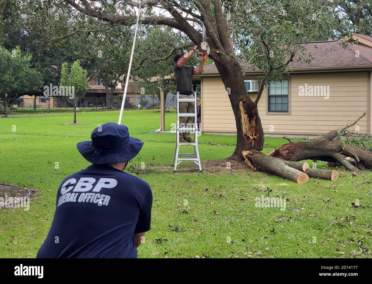 CBP-Beamte und US-Grenzschutzbeamte helfen, einen heruntergestürzten Baum in der Nähe eines Hauses in Orange, TX, zu räumen. Der Baum wurde vom Hurrikan Laura in West Texas am 26. August 2020 schwer beschädigt. CBP Stockfoto