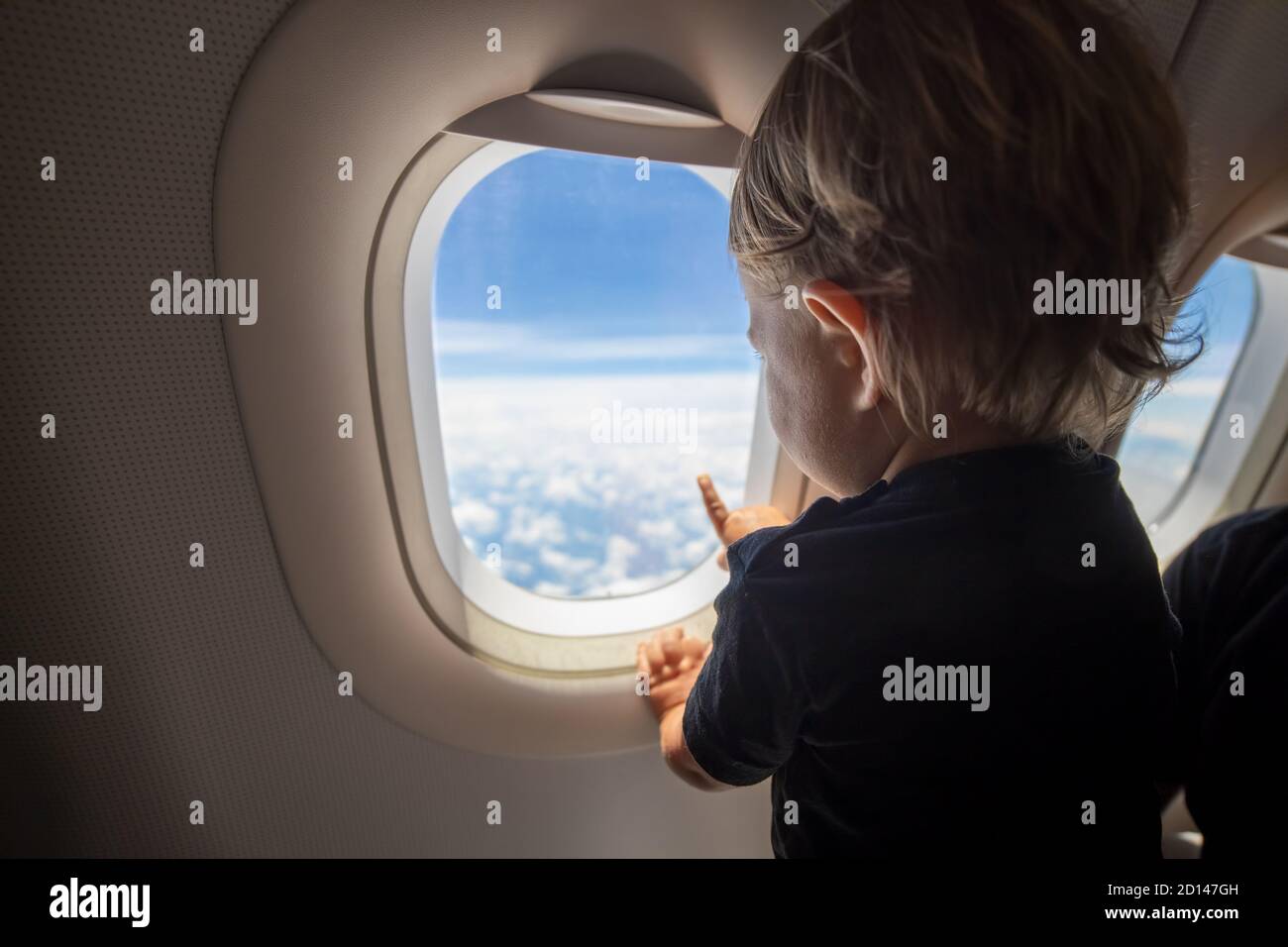 Nettes Kleinkind zeigt seinen Finger auf den Himmel durch das Fenster. First Flight Konzept, Reisen mit Kindern. Stockfoto