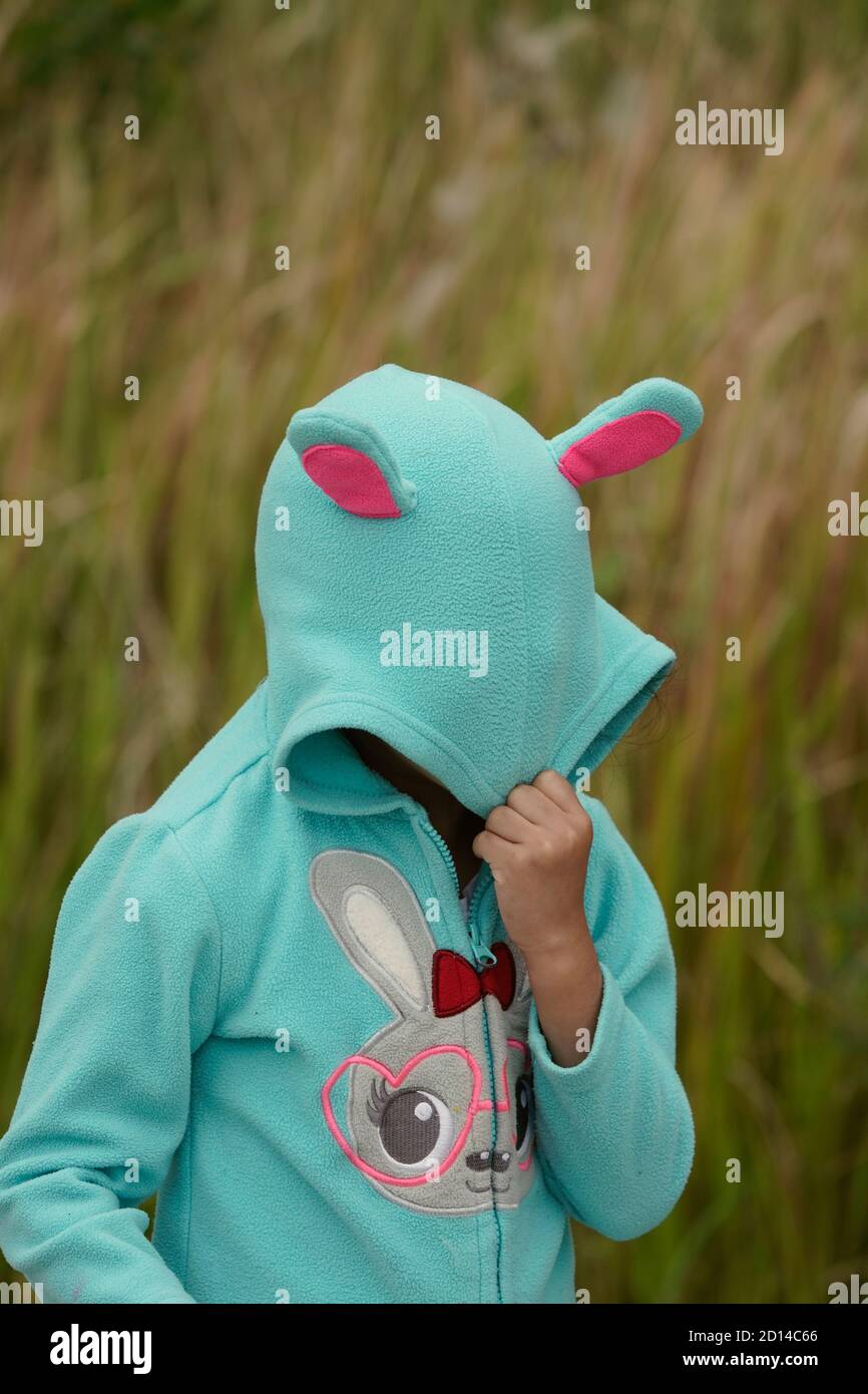 Mädchen versteckt sich hinter einem Kaninchen Hoodie Stockfoto