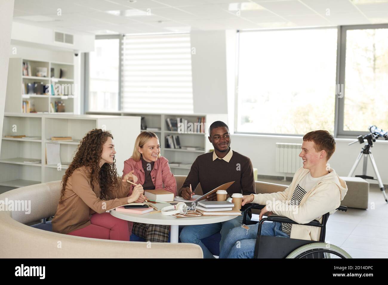 Seitenansicht auf multi-ethnische Gruppe von Studenten studieren in der College-Bibliothek mit jungen Mann mit Rollstuhl im Vordergrund, kopieren Raum Stockfoto