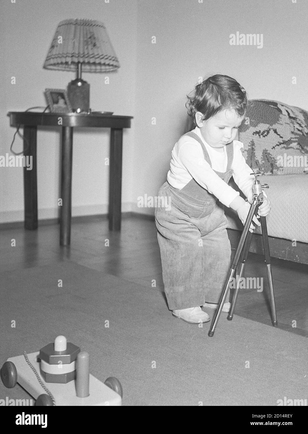 Zwei Jahre alte GirlSt ein Stativ in ihrem Wohnzimmer, USA Stockfoto