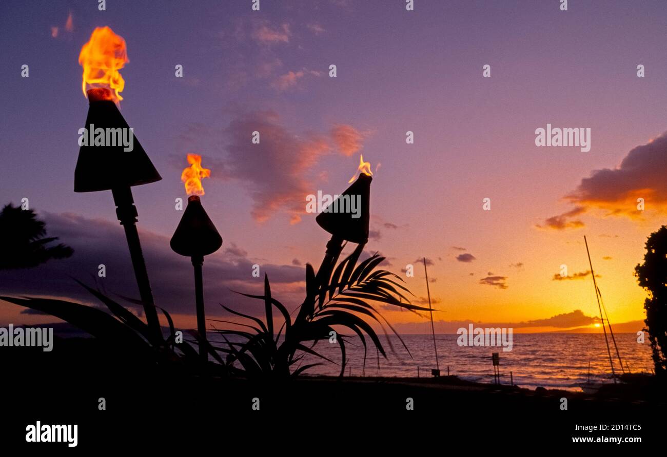 Flammendes Tiki-Fackeln erwacht zum Leben, wenn die Sonne über dem Nordpazifik auf den tropischen Hawaii-Inseln, USA, untergeht. Durch Propan oder Erdgas gefeuert, steigen die Flammen aus Metall oder Bambuskegel auf Pfosten im Boden montiert. Basierend auf polynesischer Kultur, haben Tiki-Fackeln zu Ikonen von Resorts und Restaurants in ganz Hawaii. Ihre anfängliche Popularität geht auf die 1930er-40er Jahre zurück, als die Fackeln in den Restaurants Don the Beachcomber und Trader Vic zum polynesischen Dekor gehörten. Stockfoto