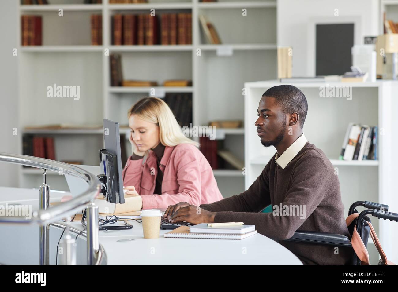 Seitenansicht Porträt des jungen afroamerikanischen Mann mit Computer während des Studiums in der College-Bibliothek, kopieren Raum Stockfoto