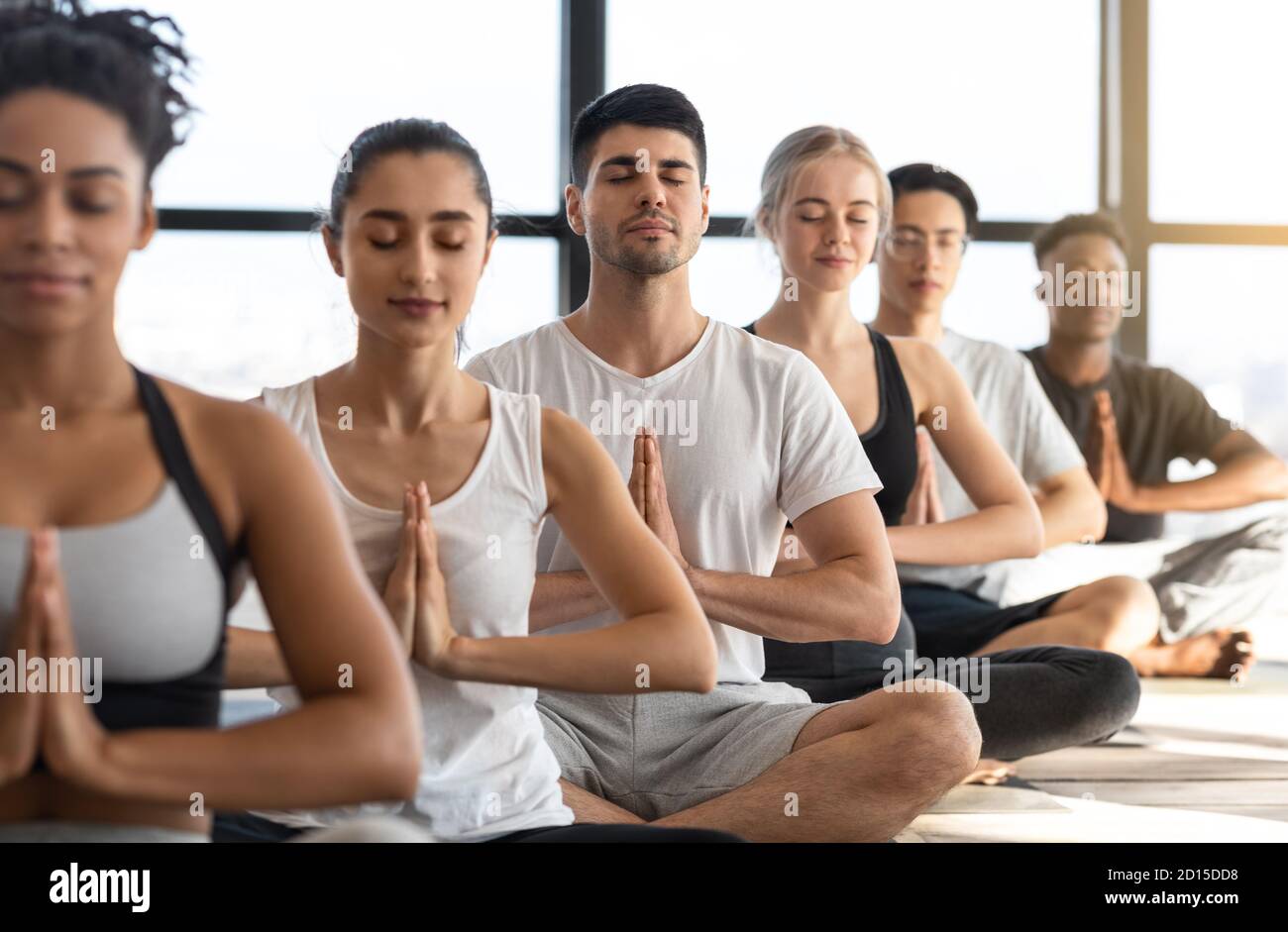 Zen. Multiethnische Gruppe Von Entspannten Menschen, Die Gemeinsam Im Yoga Studio Meditieren Stockfoto