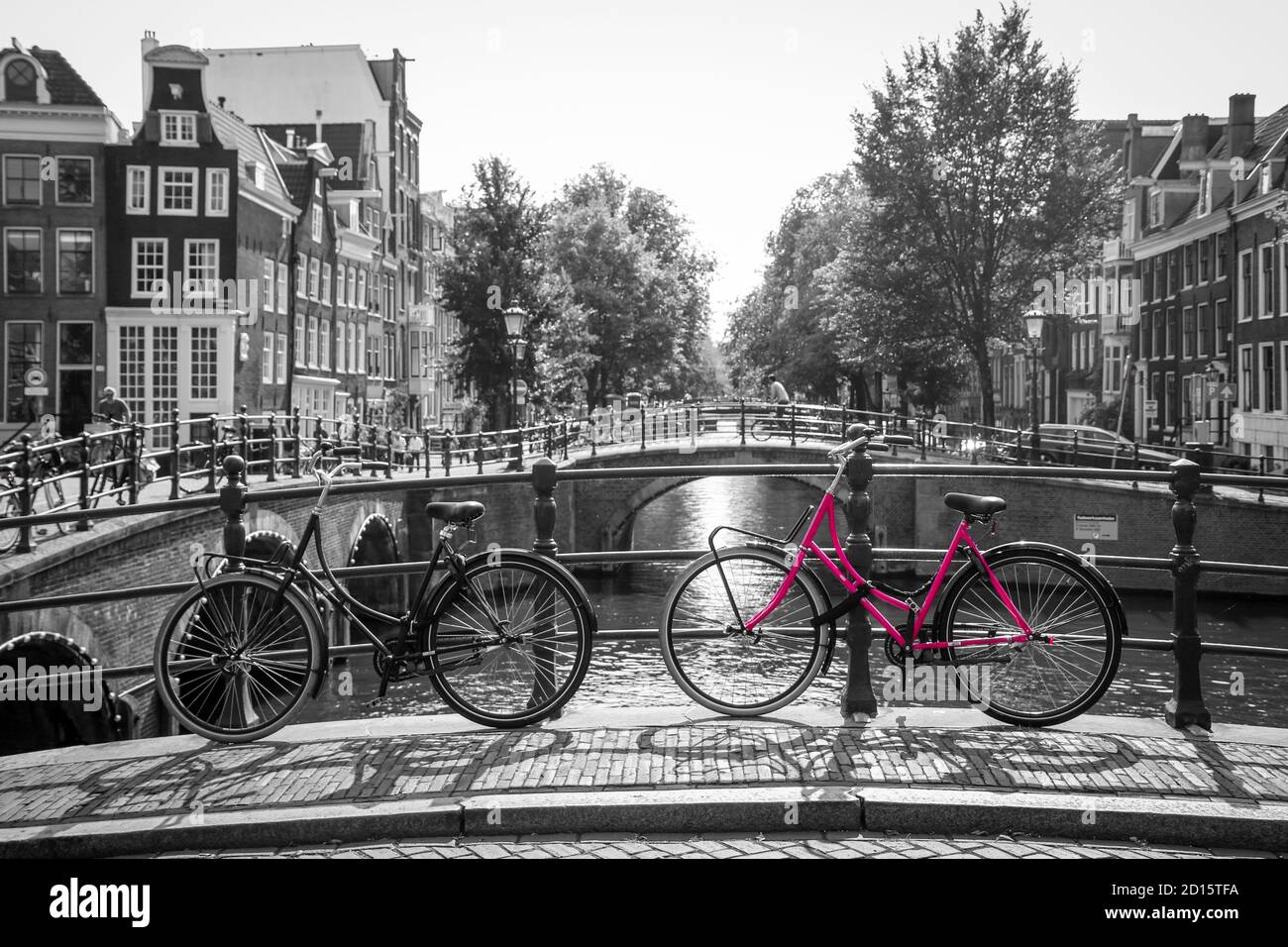 Ein Bild von einem rosa Fahrrad auf der Brücke über den Kanal in Amsterdam. Der Hintergrund ist schwarz-weiß. Stockfoto