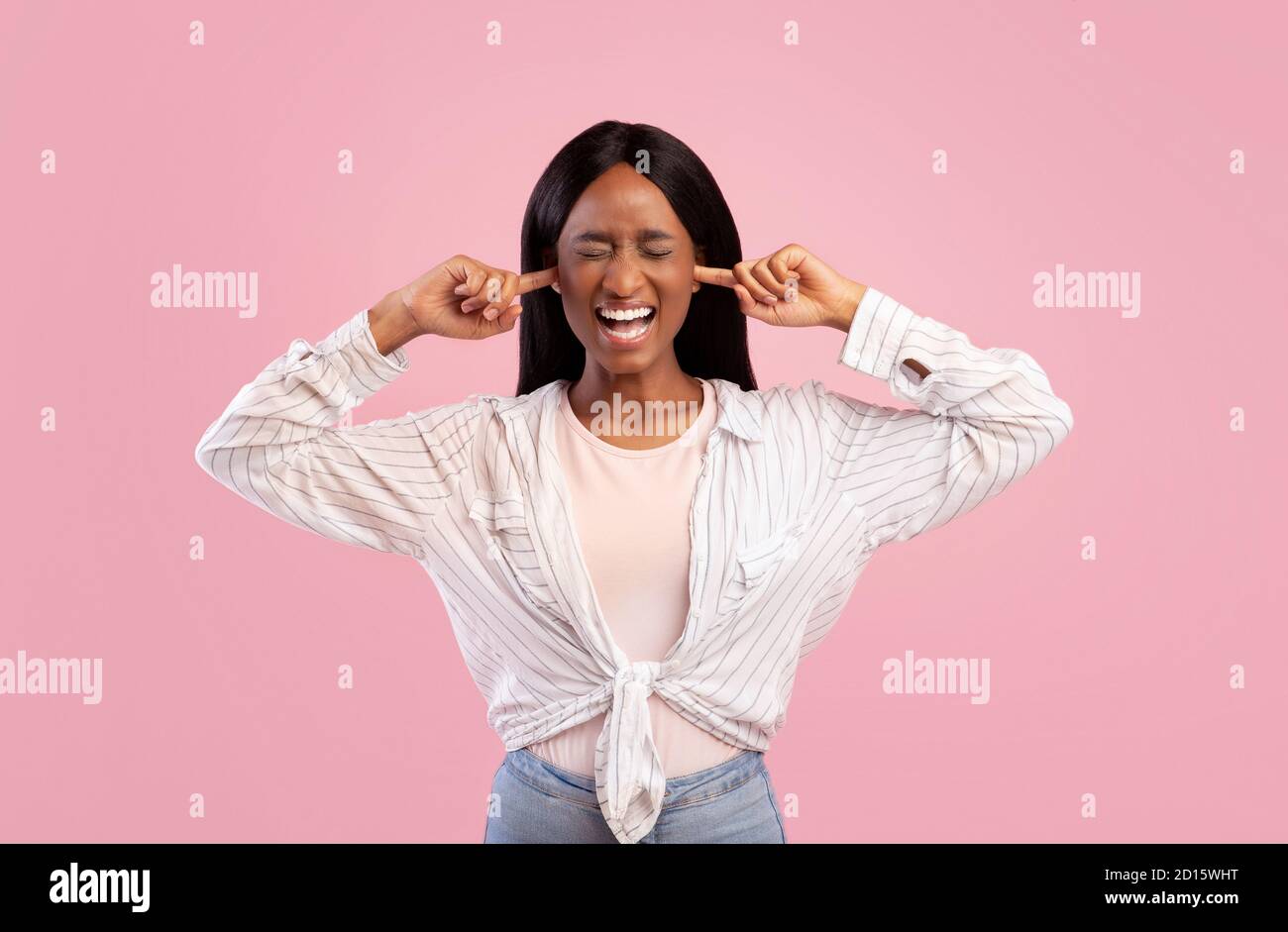 Porträt einer irritierten jungen schwarzen Frau, die die Ohren mit den Fingern schließt Und ihre Augen auf rosa Studiohintergrund schließen Stockfoto