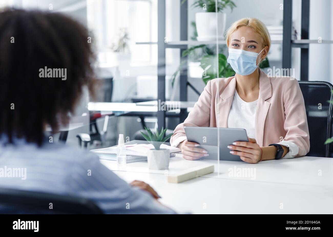 Neue normale und moderne Interview während covid-19 Ausbruch. HR-Manager mit Laptop sieht afroamerikanische Frau durch Schutzglas Stockfoto