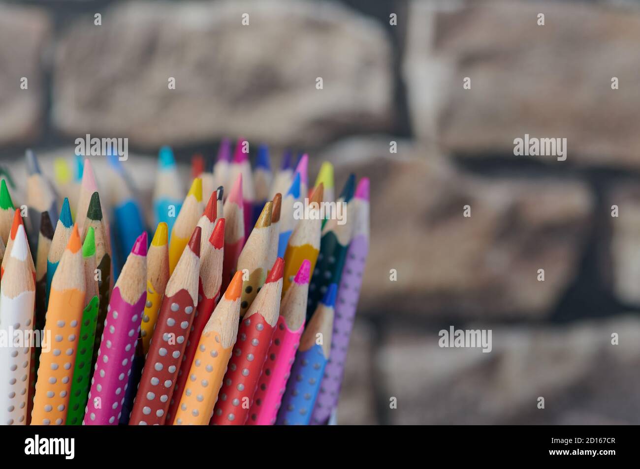 Farbige Bleistifte, Nahaufnahme vor einem verschwommenen Wandhintergrund Stockfoto