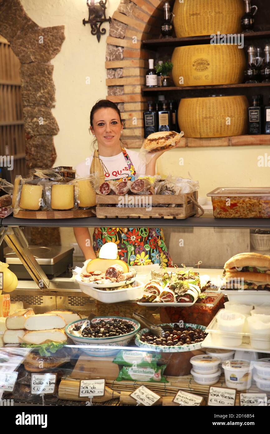 Italien, Sizilien, Taormina, Verkäuferin, die Sicilyn Käse und Wurstwaren hinter der Theke ihres lokalen Produzenshops verkauft Stockfoto