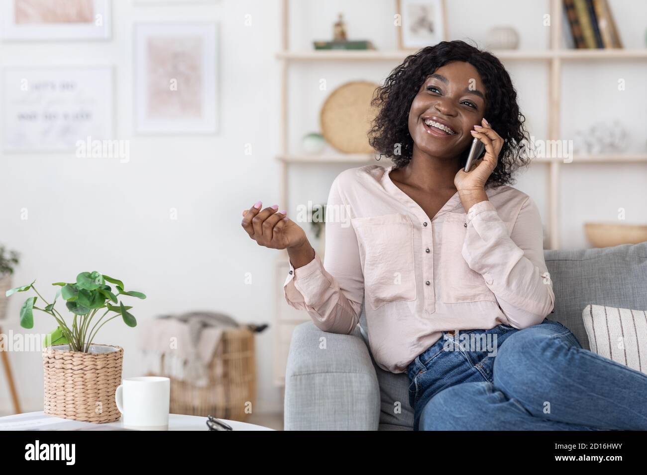 Lächelnde Schwarze Frau Im Gespräch Auf Handy Zu Hause Mit Ihr Freund Stockfoto