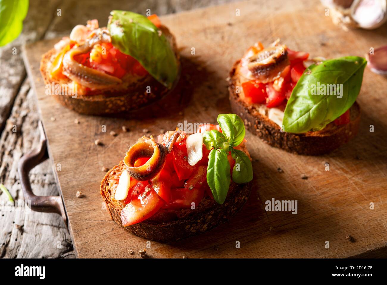 Gebratene Tomaten Bruschetta mit Tomaten Olivenöl Sardellen frischen Basilikum Stockfoto