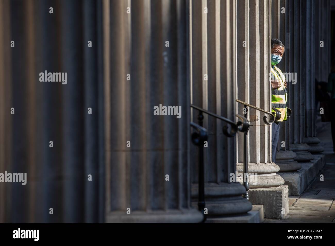 Sicherheitsdienst trägt eine Gesichtsmaske als Vorsichtsmaßnahme gegen die Verbreitung des Coronavirus steht auf der Außentreite der Eingang der Bank of England, Großbritannien Stockfoto