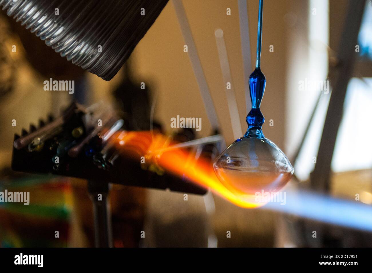Ein Glasmeister erstellen ein Glasstück mit einem typischen Flamme für Glasbläserei Stockfoto