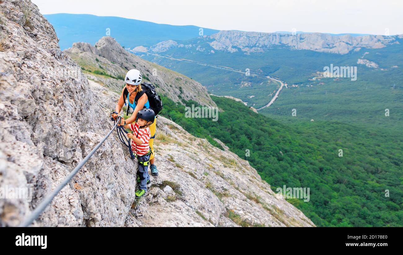 Mutter, Kind in Sicherheitsausrüstung Aufstieg zum Gipfel mit Klettersteig Anfängerroute. Familienreise Abenteuer, Wanderaktivitäten. Kinder erkunden die Natur Stockfoto