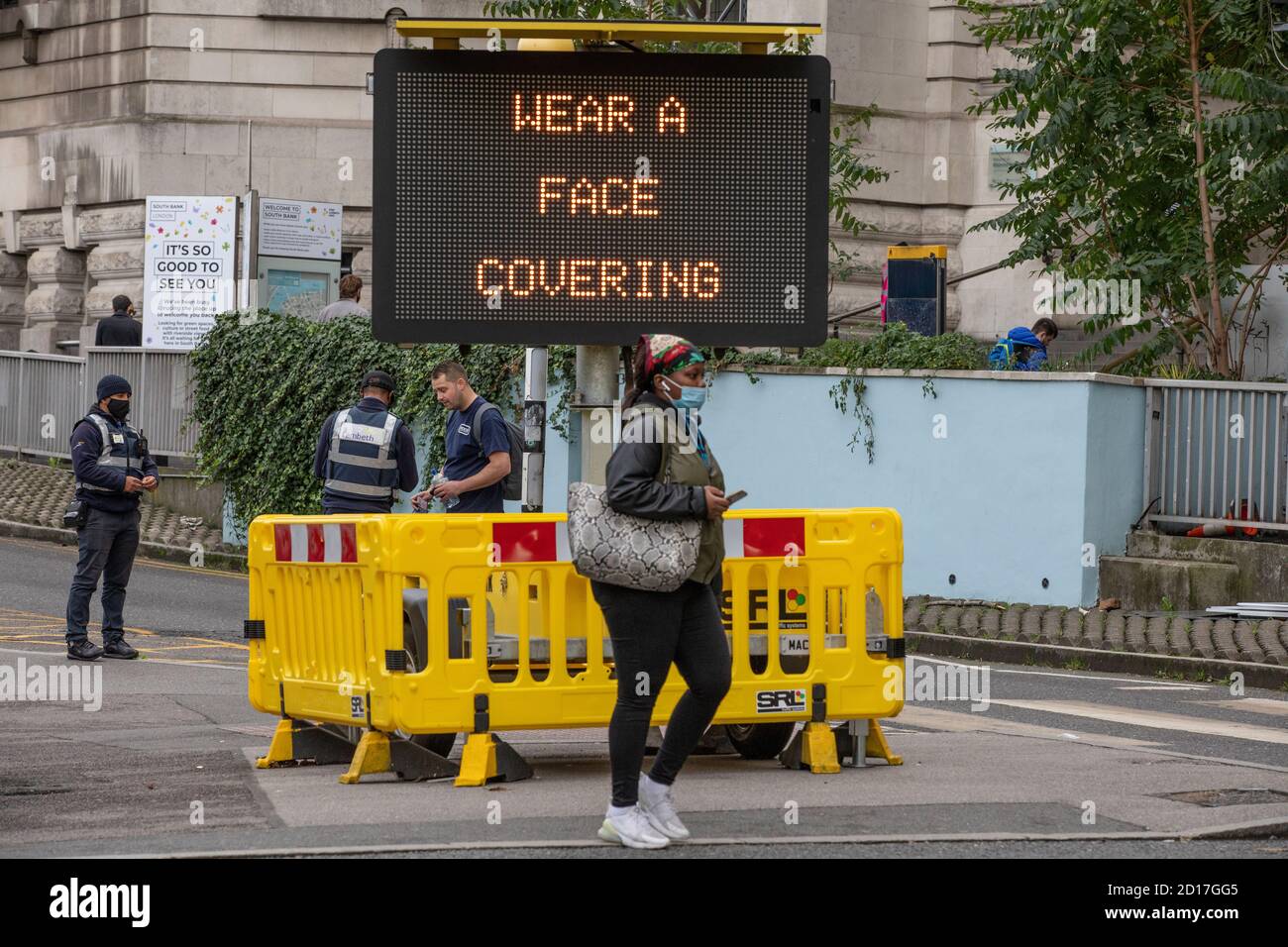 Ein Mann wird neben einem Hinweisschild "Tragen SIE EINE Gesichtsbedeckung" gewarnt, der Pendler anweist, eine Gesichtsmaske auf öffentlichen Verkehrsmitteln, Waterloo Station, Großbritannien, zu tragen Stockfoto