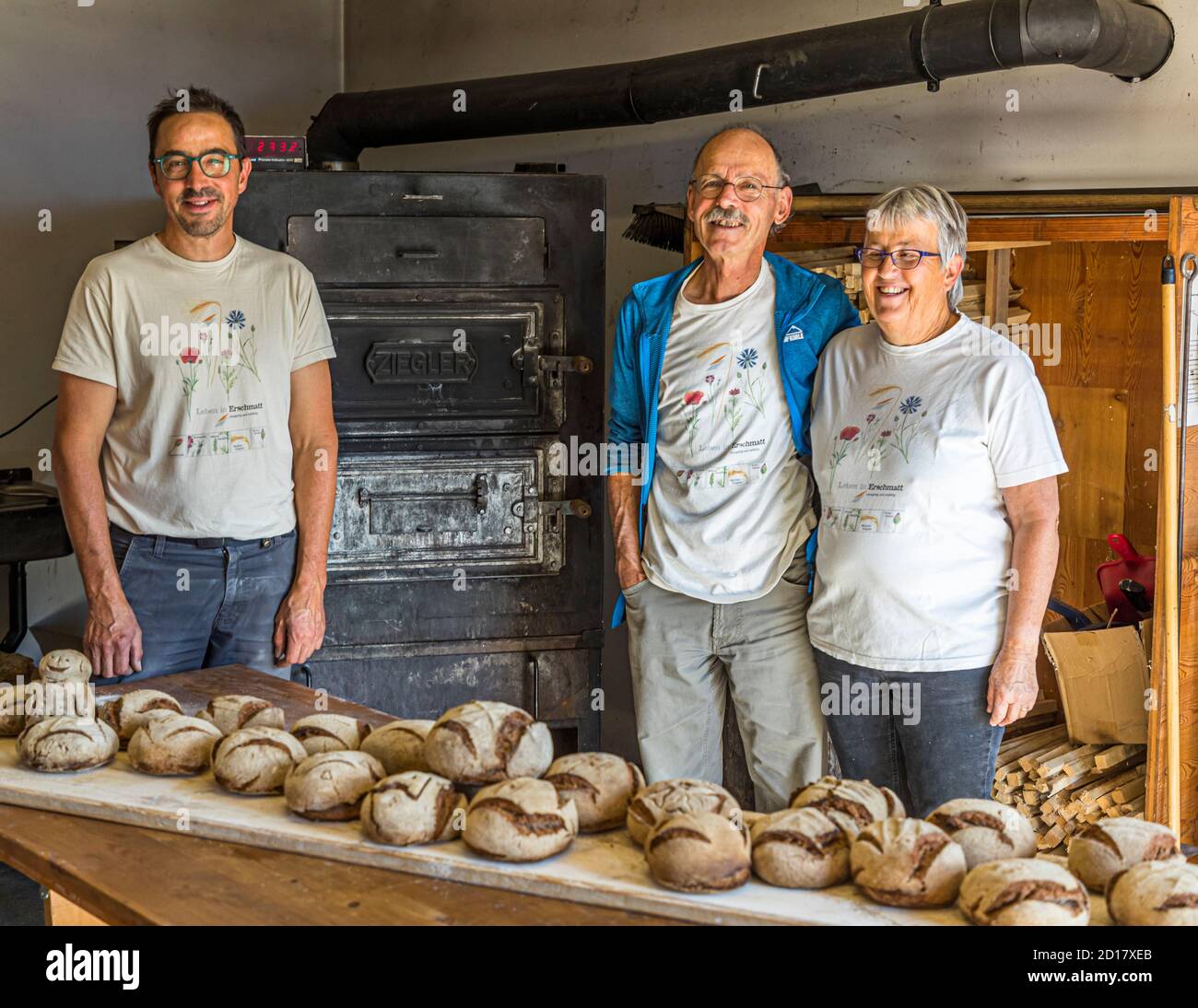 Walliser Roggenbrot-Backwerkstatt in Goppenstein-Erschmatt, Schweiz. Das Team: David Da Pieve (links), ist an diesem Tag der Ofner, der den Ofen heizt, das Brot einschießt, den Backvorgang überwacht und dafür sorgt, dass das Brot optimal gebacken wird. Edmund Steiner führt durch den praktischen Teil des Workshops. Seine Frau Marianne kümmert sich um die Koordination der gesamten Backerfahrung und bereitet das gemeinsame Mittagessen zu Stockfoto