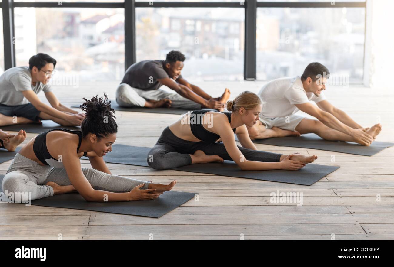 Diverse sportliche Männer und Frauen machen Stretching-Übungen in der Gruppe Yoga-Unterricht Stockfoto