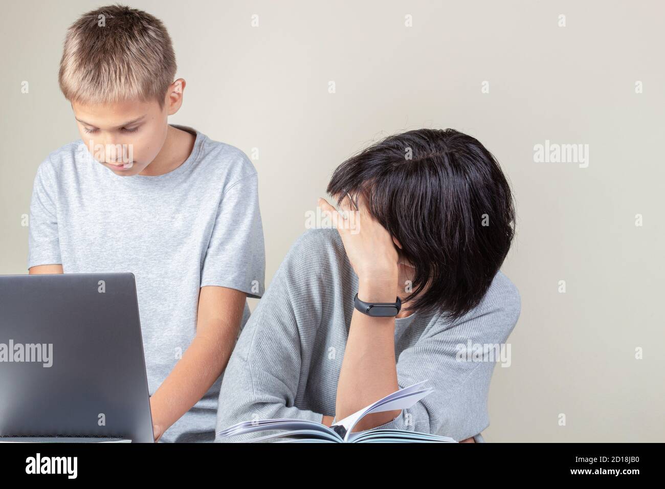 Junge hilft seiner Mutter Laptop-Computer verwenden, um für Online-Arbeit, Lernen, Videoanruf zu Hause einzurichten Stockfoto