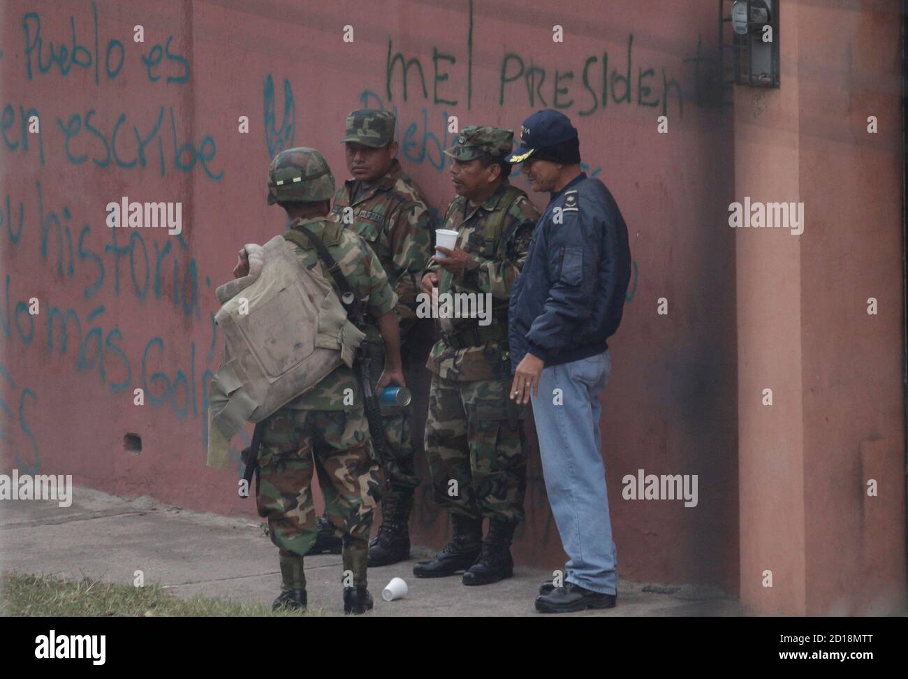 Kaffee trinken Soldaten vor der brasilianischen Botschaft in Tegucigalpa 25. September 2009. Hunderte von Soldaten und Polizei mit automatischen Waffen haben die brasilianische Botschaft umgeben, wo Zelaya mit seiner Familie und rund 40 Helfern trotz Essen und Wasserknappheit im Gebäude Zuflucht ist.  Die Graffiti an der Wand liest "Mel (Zelaya) Präsident".    REUTERS/Edgard Garrido (HONDURAS-Politik-Konflikt) Stockfoto